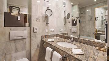 Un baño moderno con encimera de granito, lavamanos dobles, un espejo grande y un perchero.