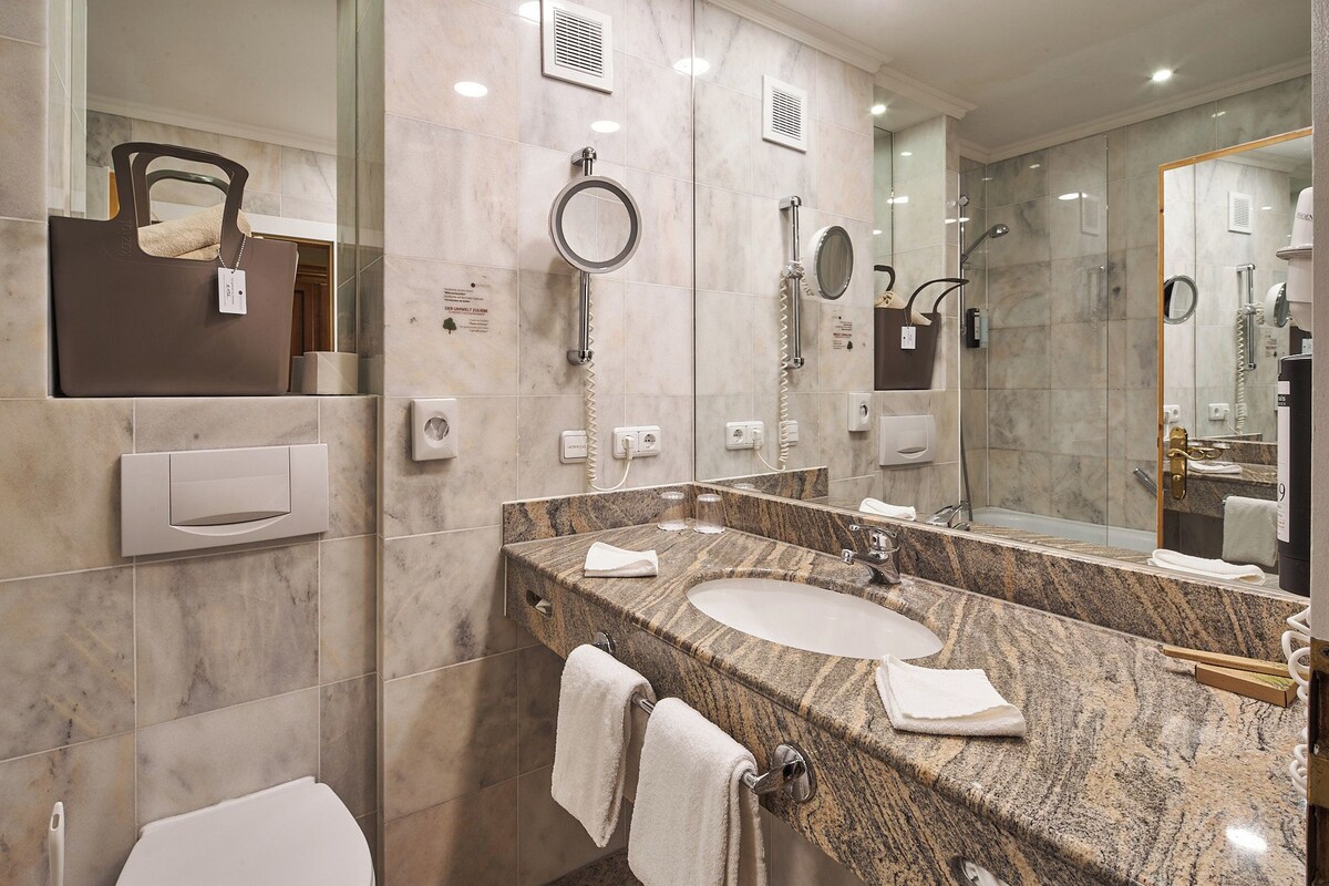 Une salle de bain moderne avec un comptoir en granit, deux vasques, un grand miroir et un porte-serviettes.