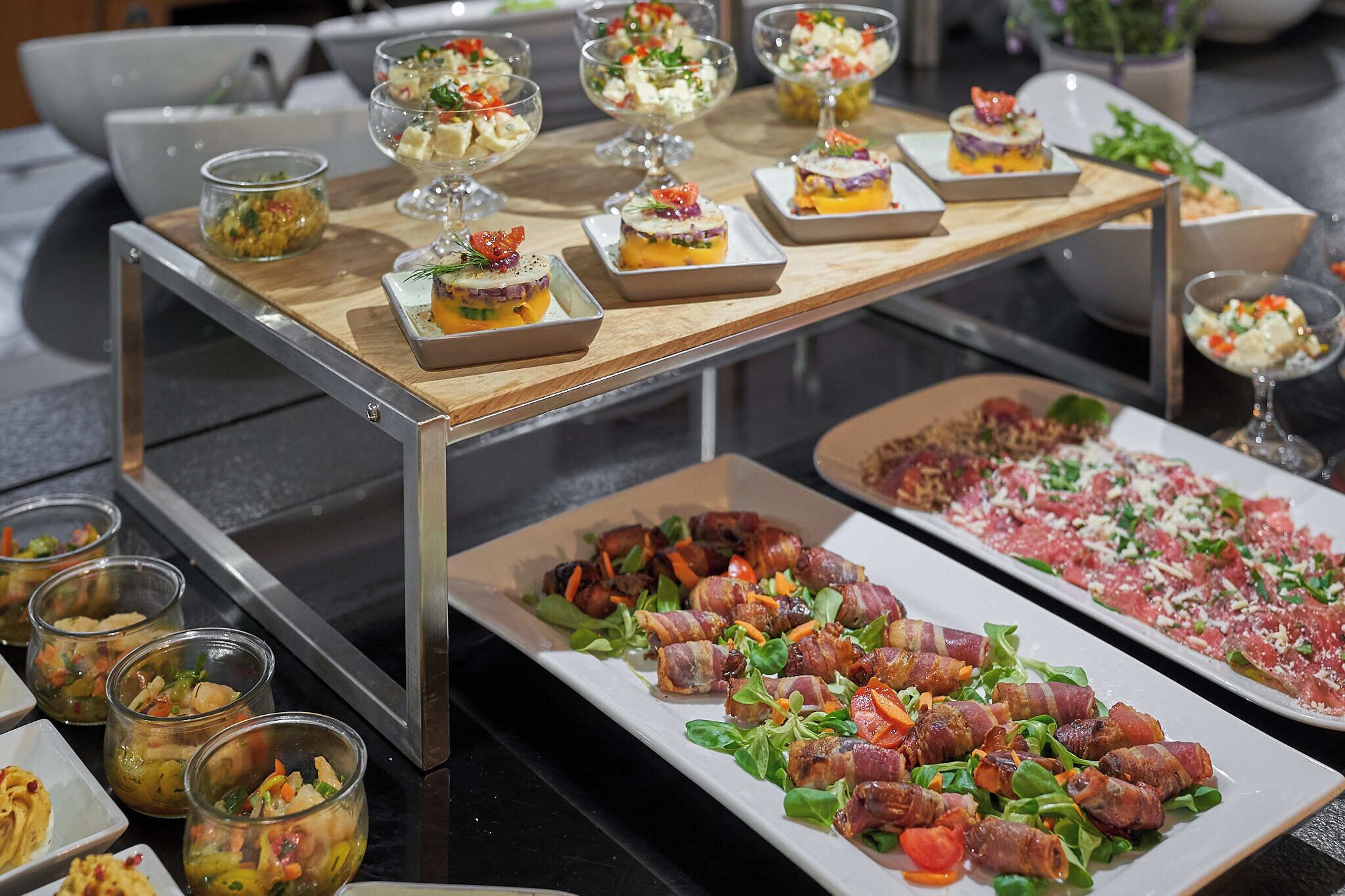 Taula de buffet amb diversos plats, incloent amanides, tastets i un gran plat de carn.