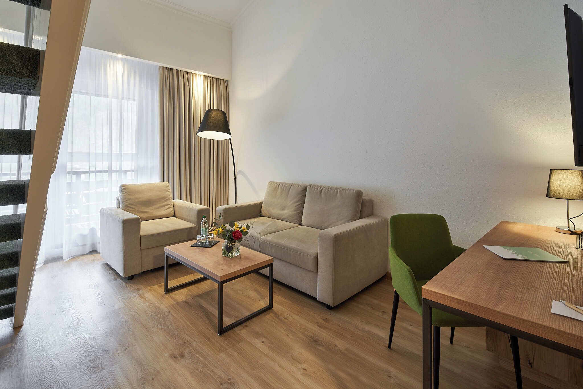 A modern living room with a sofa, a coffee table, a dining table, and a lamp.