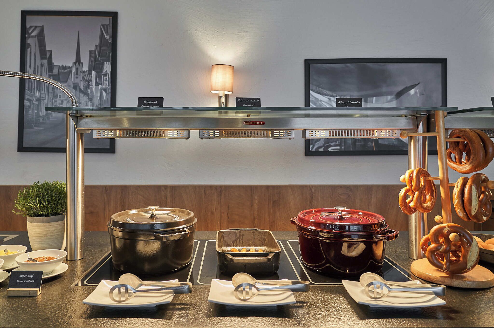 A buffet setup with various food items, a lamp, and framed pictures on the wall.