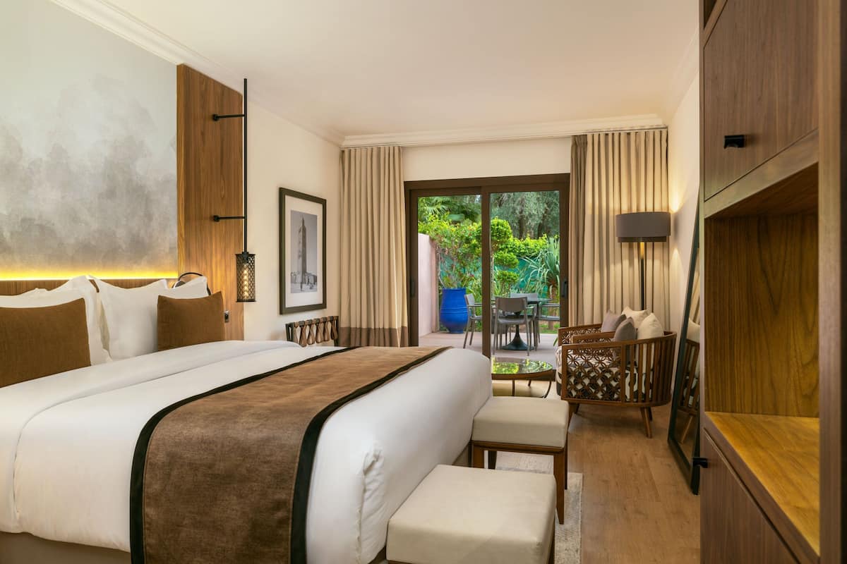 A hotel room with a large bed, a desk, a chair, and a view of the outdoors.