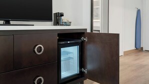 Egy modern konyha beépített hűtőszekrénnyel, kávéfőzővel és egy síkképernyős televízióval, mely a munkalapra van helyezve.