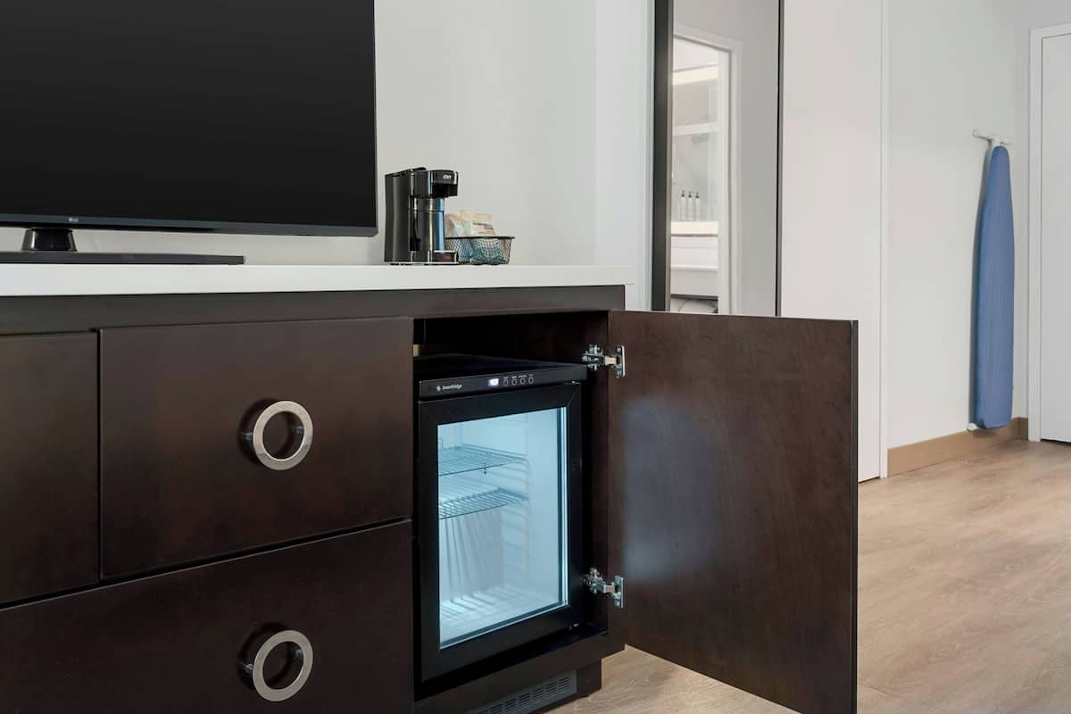 A modern kitchen with a built-in refrigerator, a coffee maker, and a flat-screen TV on the countertop.