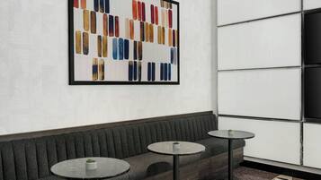 Un intérieur moderne avec un canapé, deux tables rondes et un grand tableau abstrait accroché au mur.
