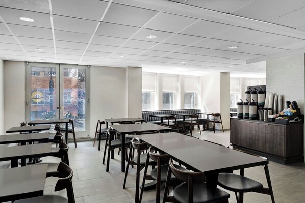 Un comedor moderno con mesas y sillas, un área de estar y una estación de café.