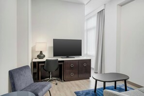 A hotel room with a desk, chair, television, and a small table. - Fairfield Inn & Suites Chicago Downtown / Magnificent Mile (Chicago)