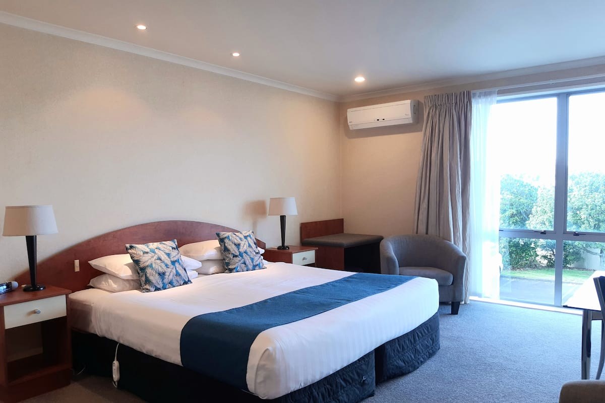 A hotel room with a large bed, two bedside tables with lamps, a desk, and a chair.