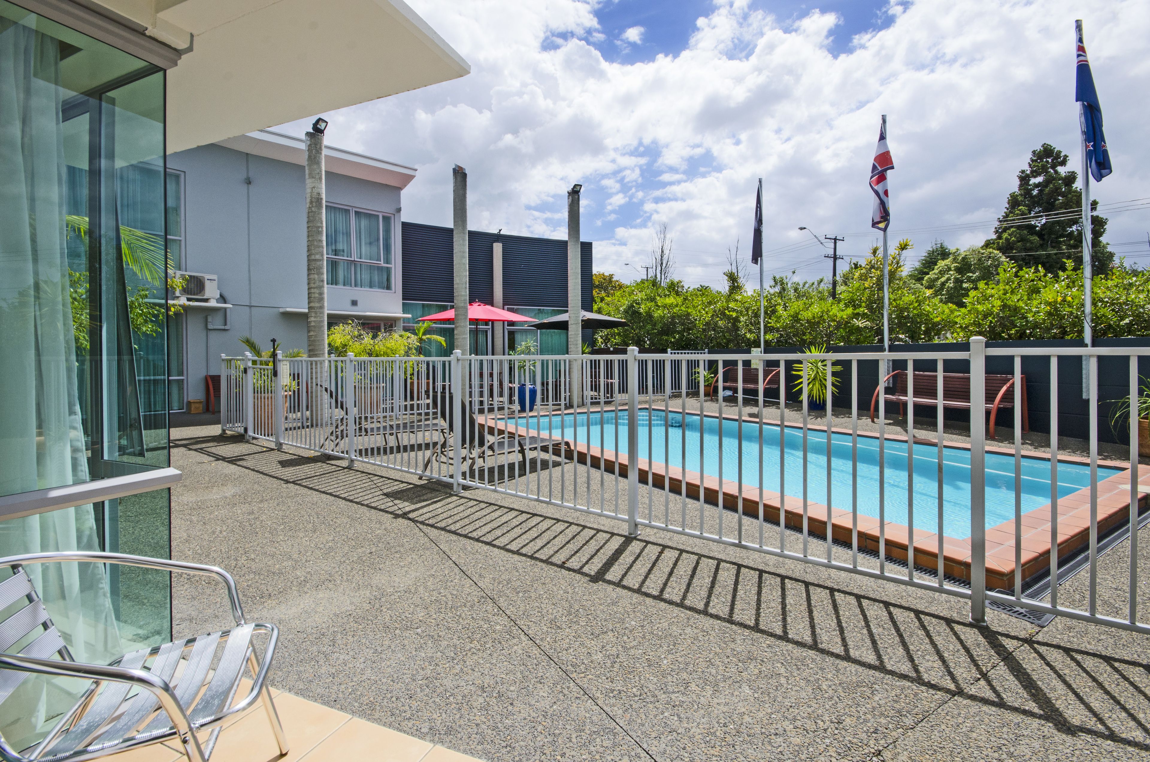 A swimming pool with a white fence, a glass balustrade, and a chair.