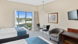 A hotel room with two beds, a desk, a chair, a television, and a large window with a view of the city. - Aristotles North Shore (Auckland)