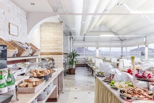 Un angolo buffet con diversi cibi e bevande, una parete in mattoni e vista sulla città.