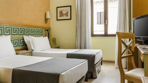 Une chambre d’hôtel avec deux lits, une télévision, un bureau et une fenêtre avec des rideaux.