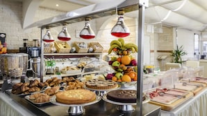 Un buffet proposant une variété de plats, notamment des fruits, des pâtisseries et des desserts.