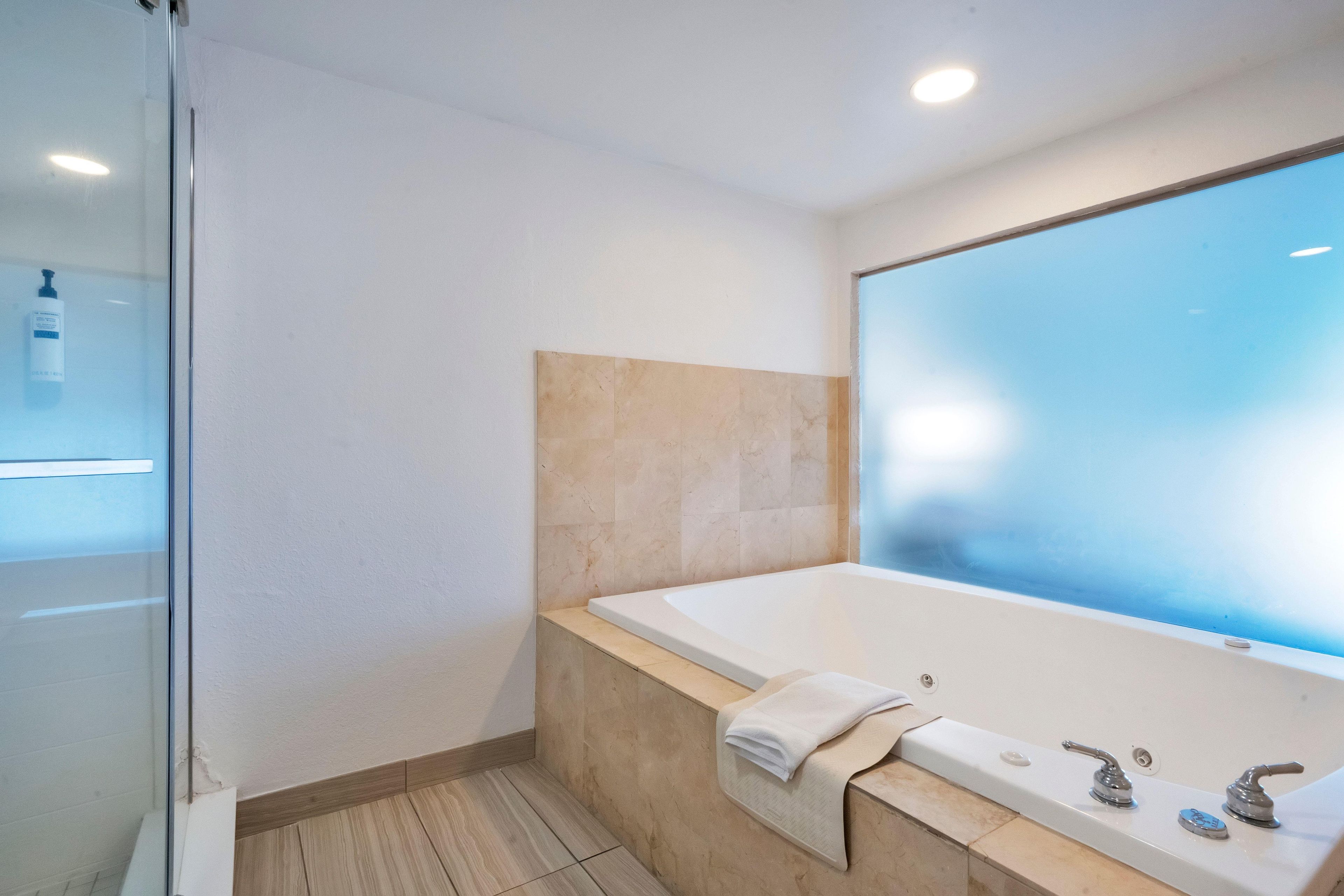 Un baño moderno con bañera, cabina de ducha de vidrio y un espejo grande.