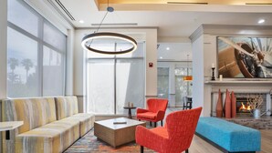 Un moderno vestíbulo de hotel con un sofá, sillas, una mesita de centro y una chimenea.