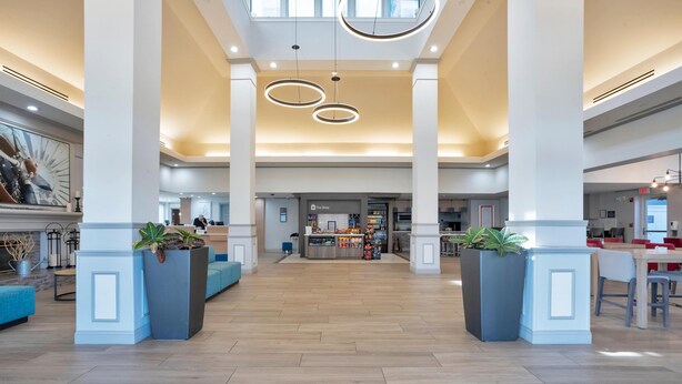 Un lobby espacioso con techos altos, iluminación moderna y una zona de recepción central.