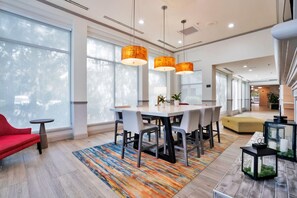 A modern dining area with a wooden table, grey chairs, and a colorful rug. - Hilton Garden Inn Jacksonville Airport (Jacksonville)