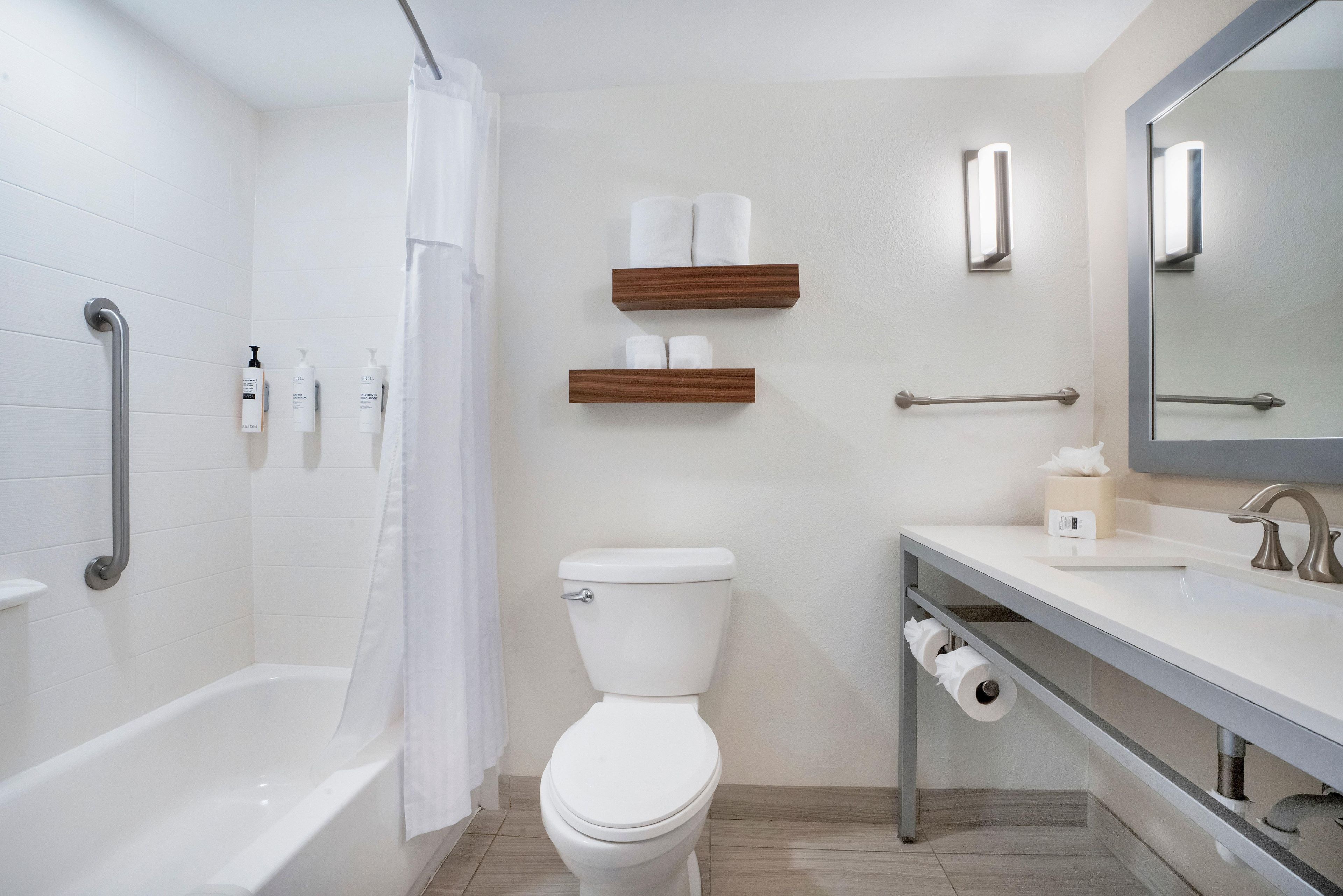 A modern bathroom with a bathtub, toilet, and vanity.