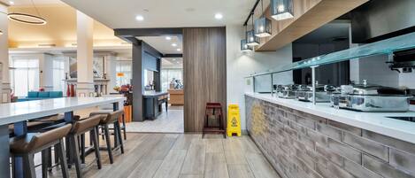 A modern kitchen with a brick backsplash, stainless steel appliances, and a bar area with stools.
