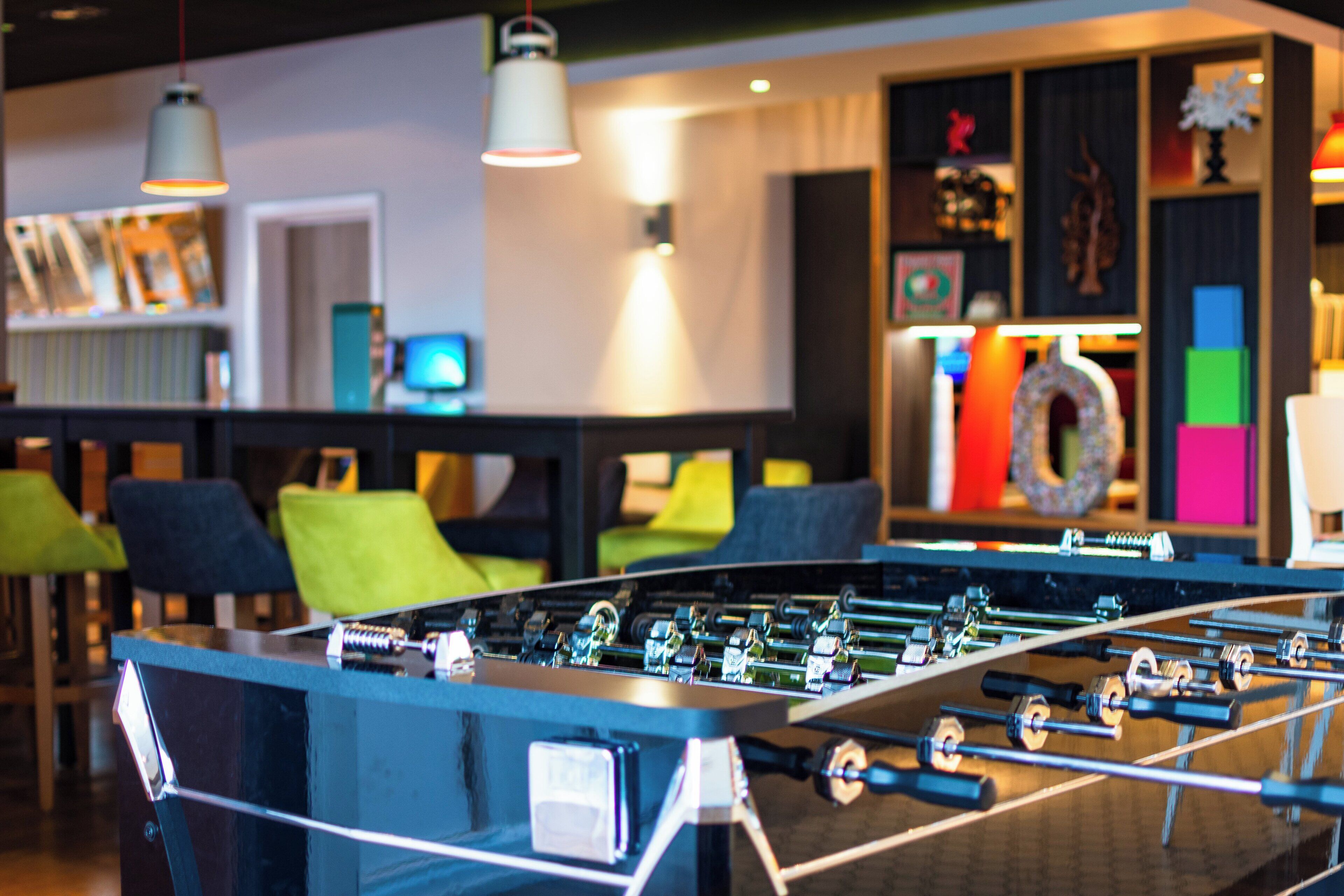 A foosball table in a room with seating and a TV in the background.