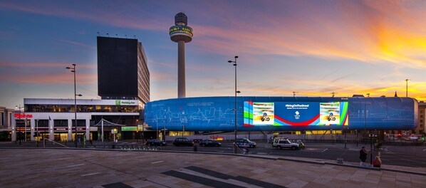 Um edifício moderno com uma torre imponente, um grande painel de tela digital e a placa Holiday Inn.