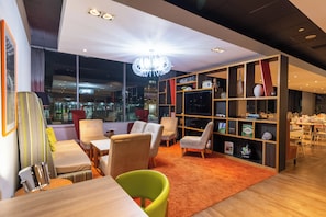 Un intérieur moderne comprenant un coin salon, une bibliothèque et une vue dégagée grâce à de grandes fenêtres.
