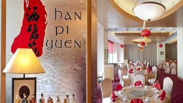 Una tradizionale camera cinese con una mappa rossa e calligrafia, un tavolo rotondo apparecchiato per la cena e un lampadario.