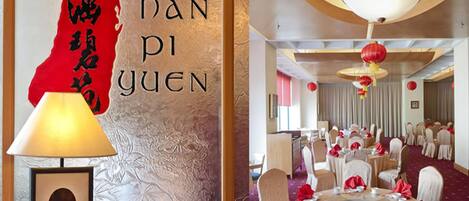 A traditional Chinese room with a red map and calligraphy, a round table set for dining, and a chandelier.