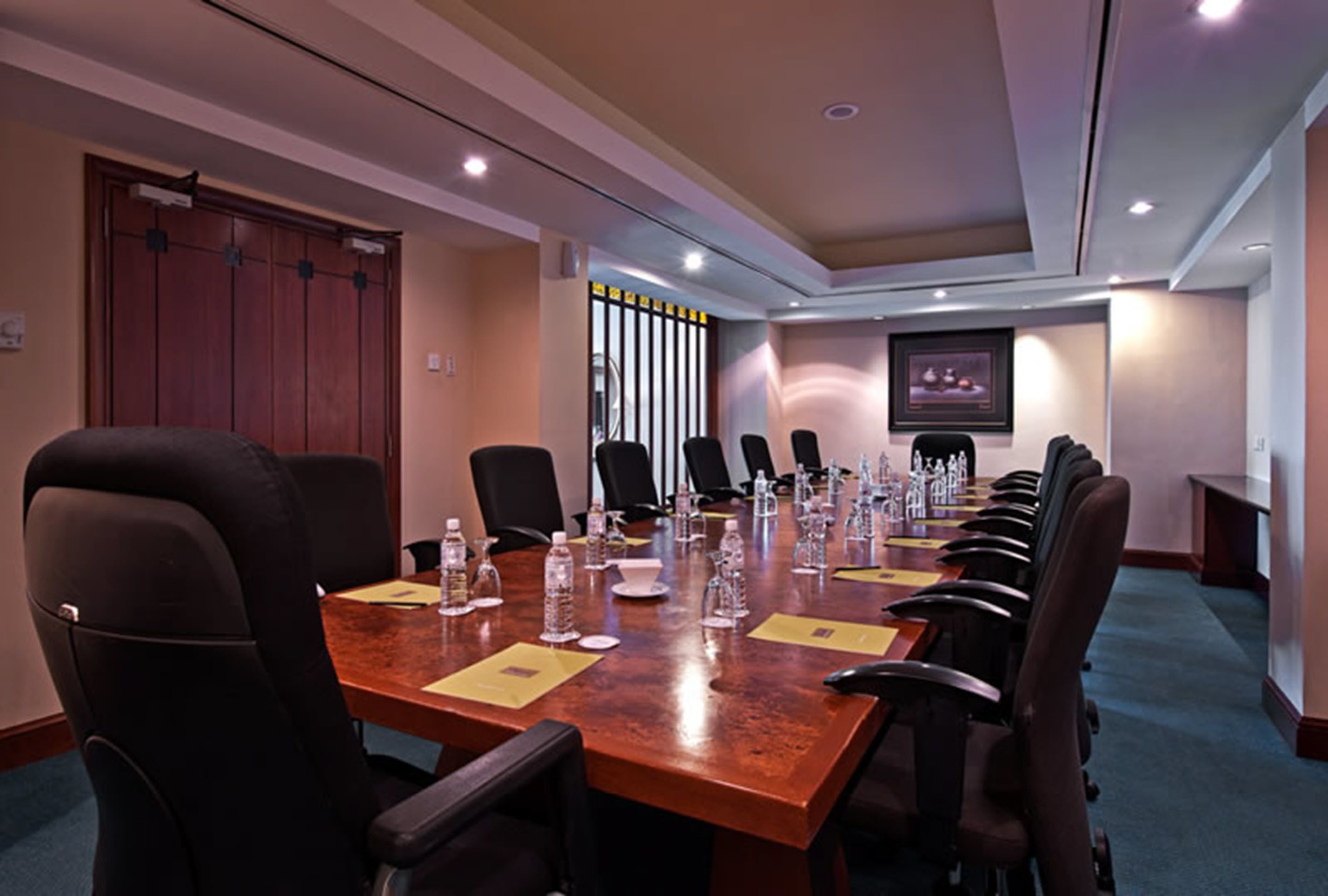 A conference room with a long table, multiple chairs, water bottles, and documents.