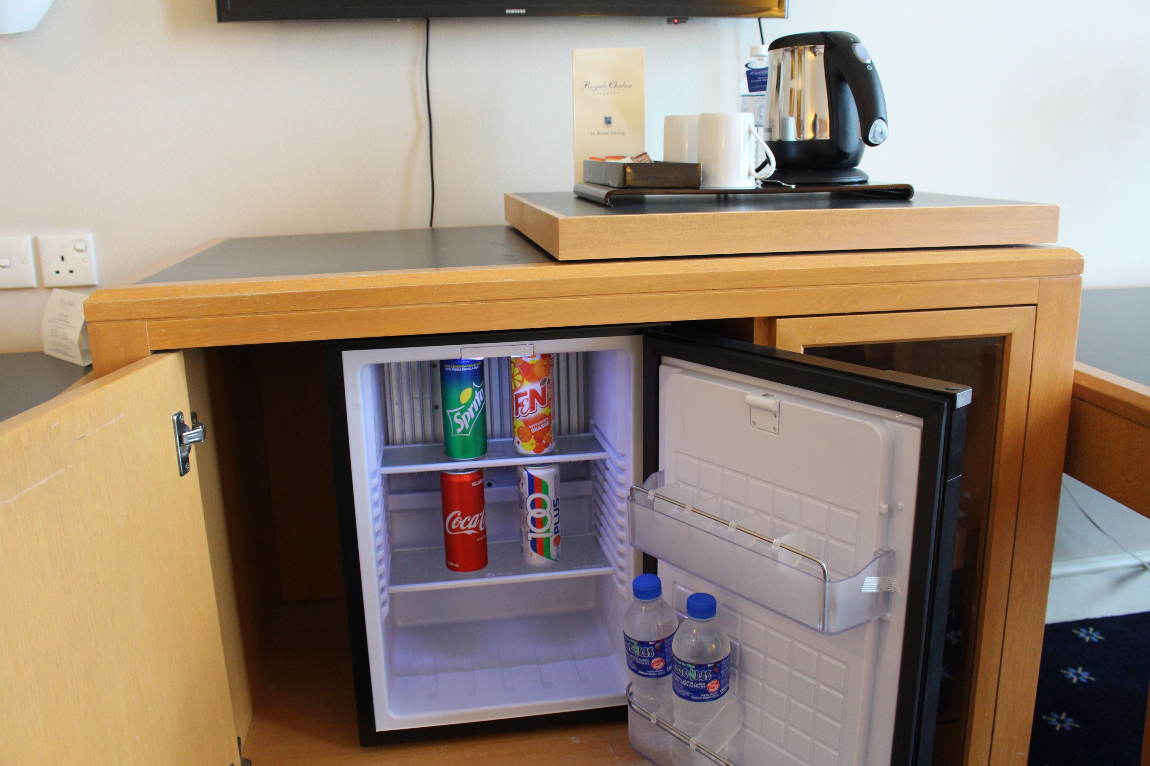 Un refrigerador compacto con una estantería de bebidas y un microondas encima.