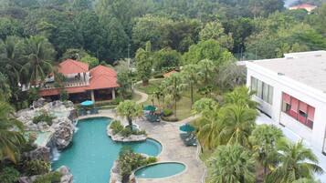 Relax by the multi-pool area surrounded by lush greenery and palm trees.