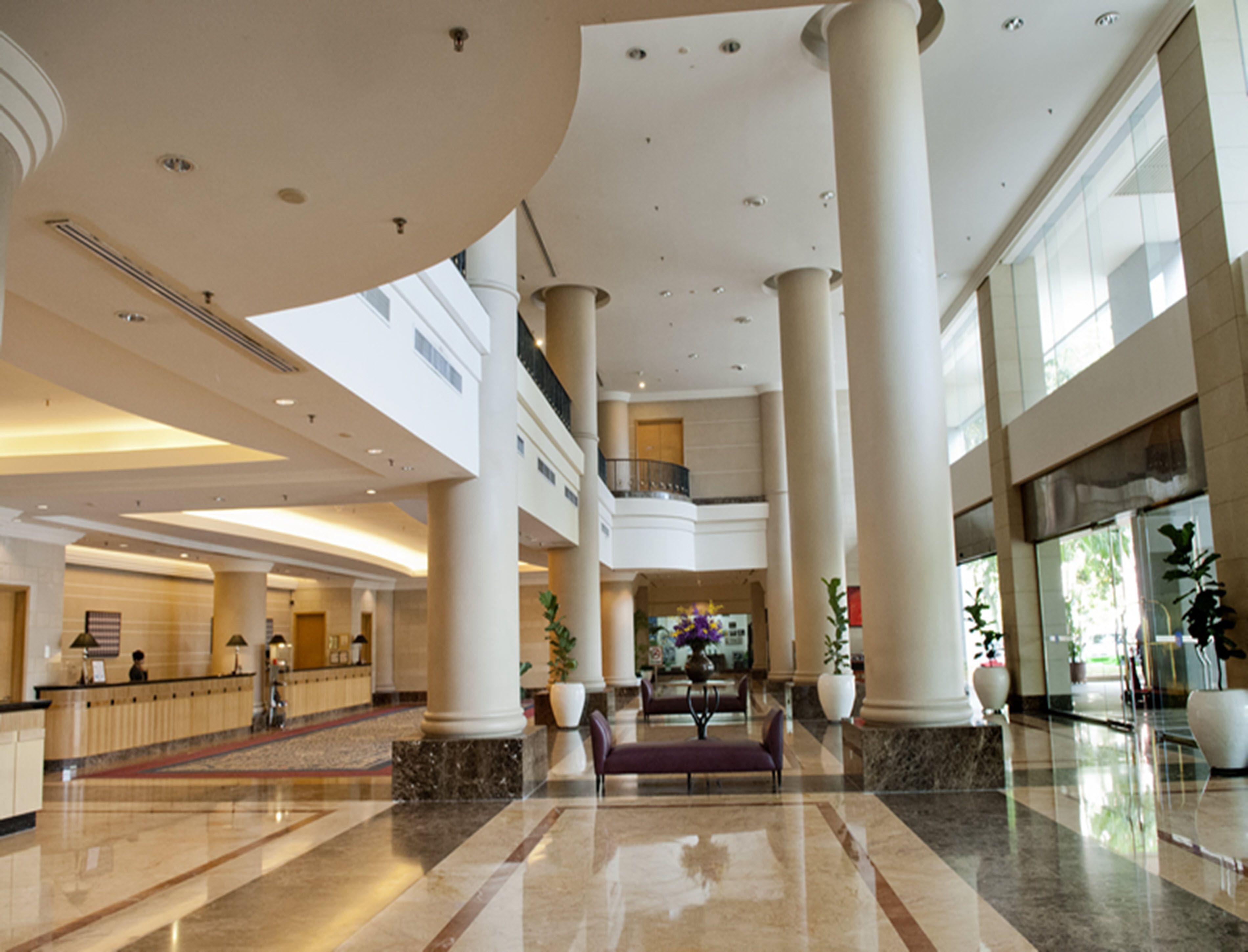 A spacious lobby with high ceilings, large columns, and a marble floor.