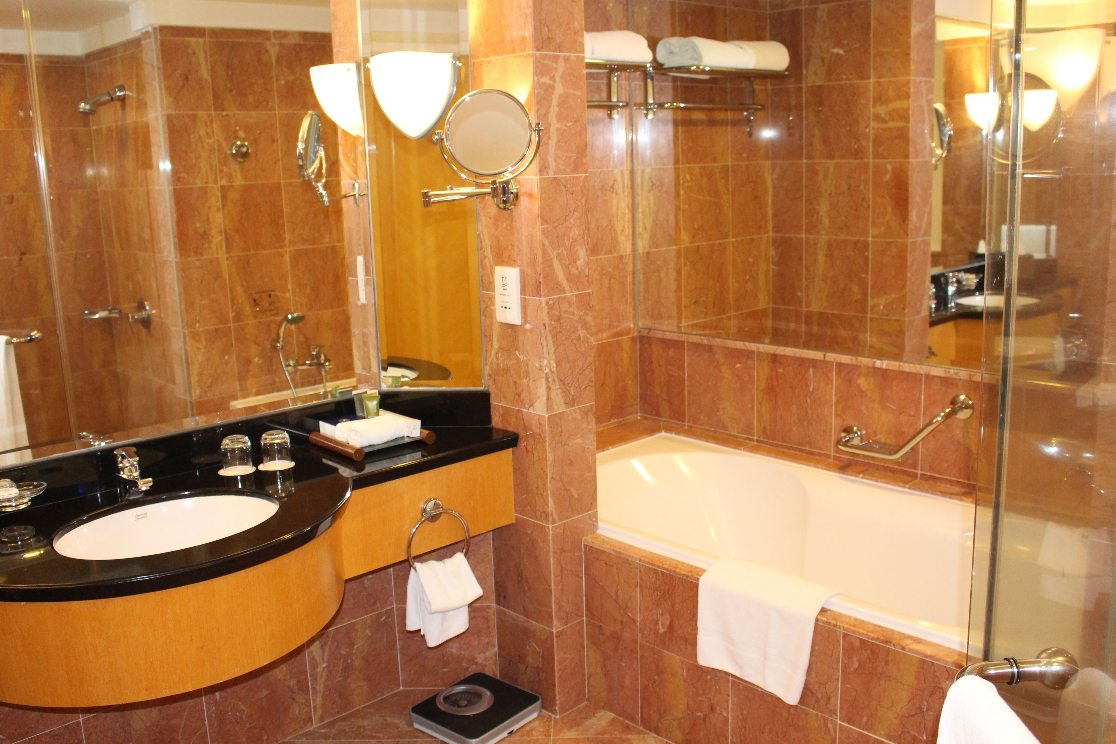 A bathroom with a black sink, white bathtub, and a glass shower enclosure.