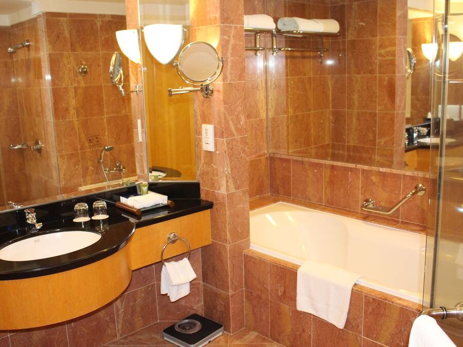 Un baño con un lavamanos negro, bañera blanca y cabina de ducha de vidrio.