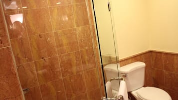 A bathroom with a glass-enclosed shower, a white toilet, and a marble-tiled floor.