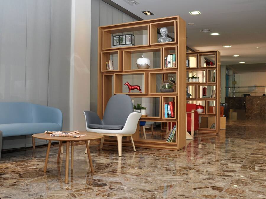 Un hall d’entrée moderne avec un canapé bleu, une bibliothèque en bois et un sol en marbre.