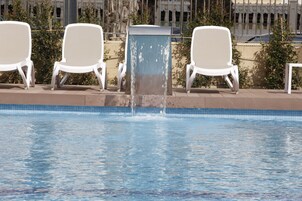 Una piscina al aire libre, sillones reclinables de piscina