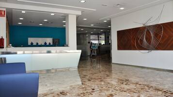 A modern reception area with a marble floor, a blue seating area, and a contemporary art piece on the wall.