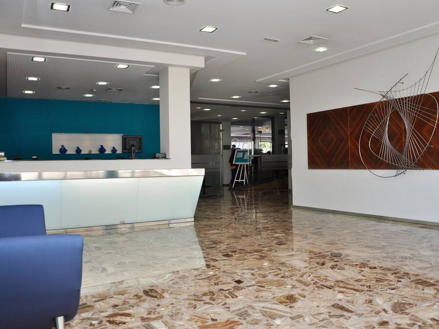 A modern reception area with a marble floor, a blue seating area, and a contemporary art piece on the wall.
