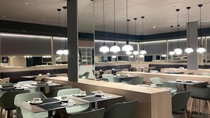 A modern dining area with multiple tables and chairs, a central counter, and pendant lighting. - HOTEL SANT PAU (Barcelona)