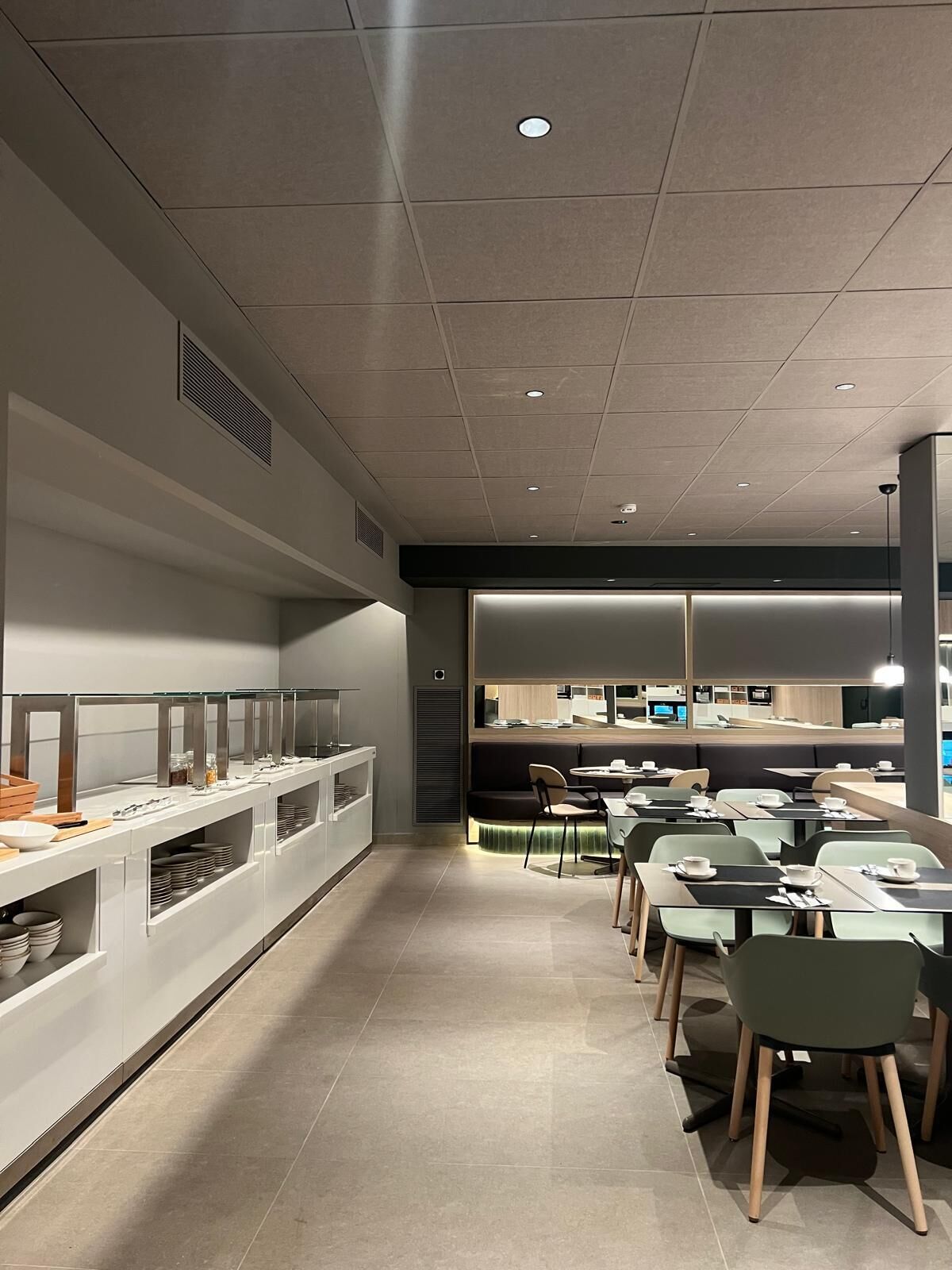 Moderni ravintola, jossa on pitkä tiski, useita pöytiä ja tiskialueen läheisyydessä oleva oleskelualue.