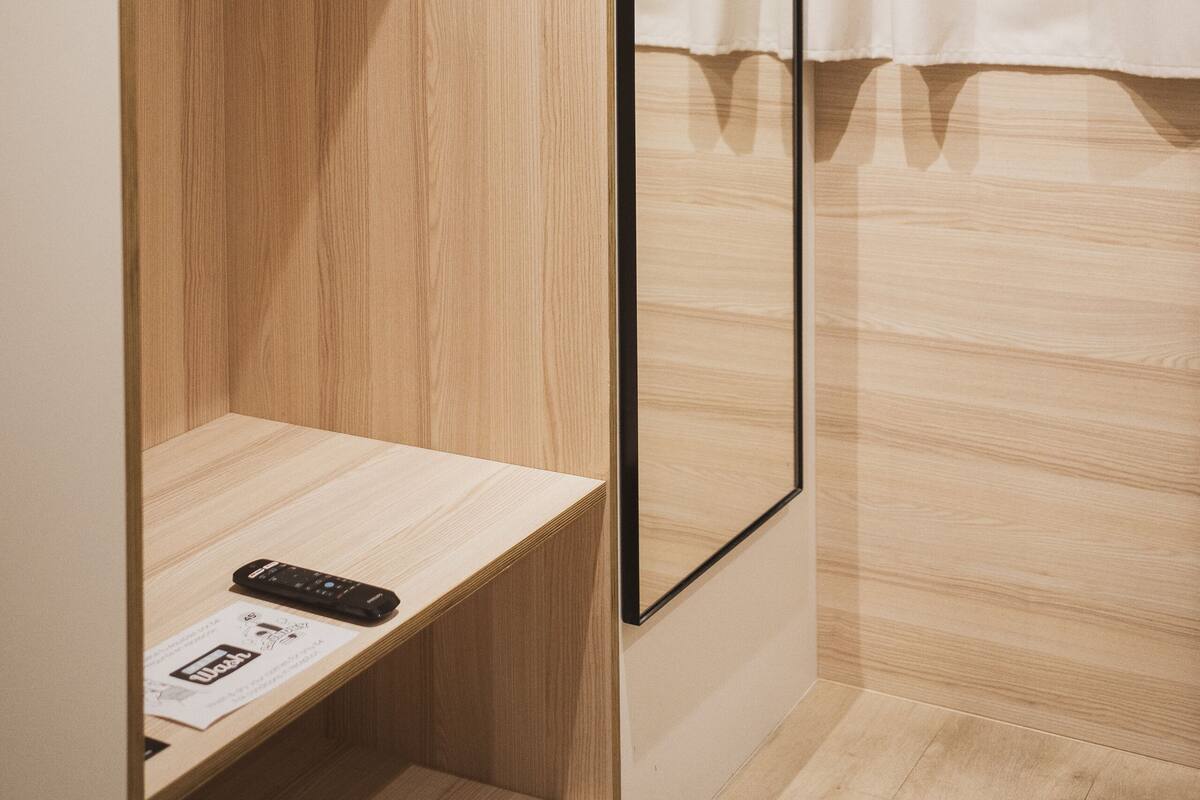 Una habitación de hotel con un armario de madera, un espejo y una cama.