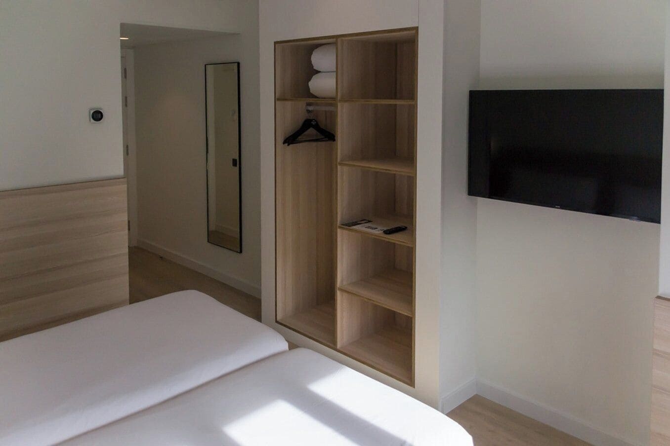 Ein Schlafzimmer mit einem Bett, einem Kleiderschrank, einem Spiegel und einem Fernseher.