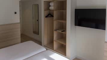 Ein Schlafzimmer mit einem Bett, einem Kleiderschrank, einem Spiegel und einem Fernseher.
