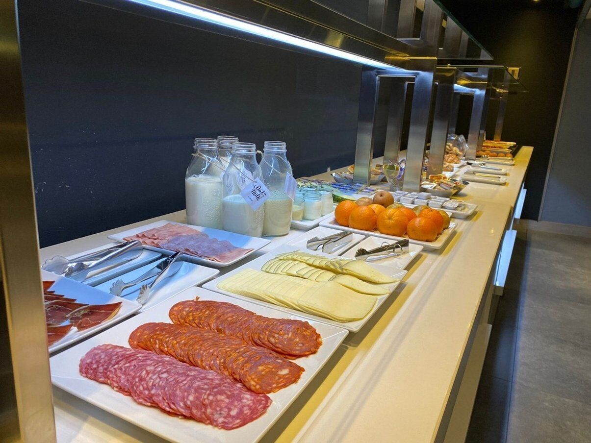 A buffet with various food items including meats, cheeses, and fruits.