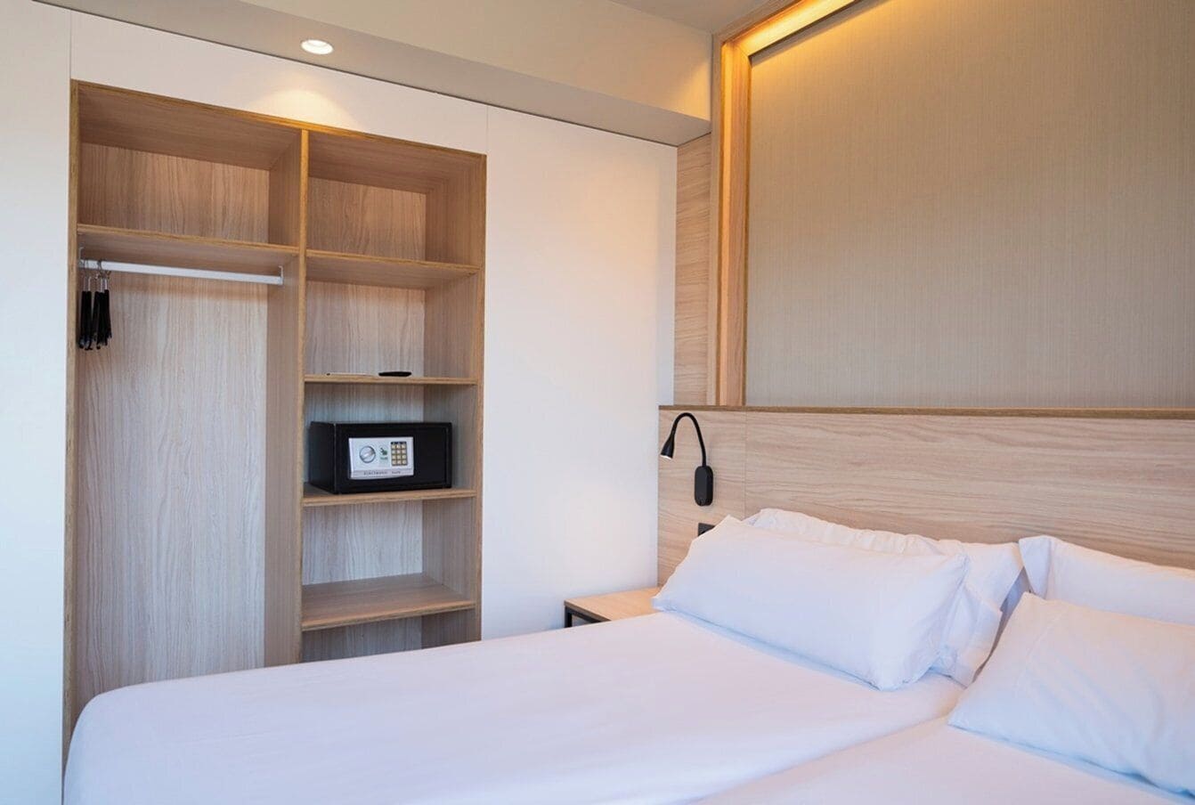 Een hotelkamer met een bed, een garderobe met meerdere planken en een nachtkastje.