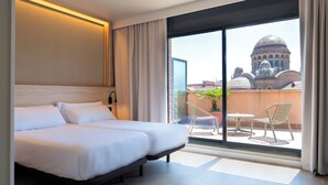 A hotel room with a large bed, a view of a building with domes, and a balcony with chairs and a table. - HOTEL SANT PAU (Barcelona)