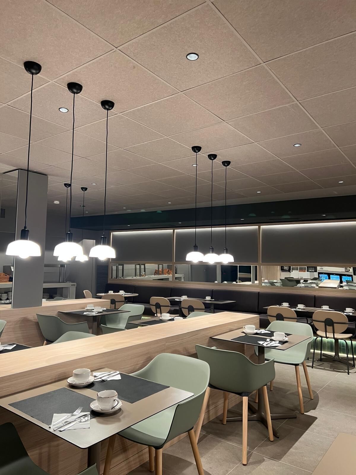 Un restaurante moderno con una barra larga, varias zonas de estar e iluminación colgante.
