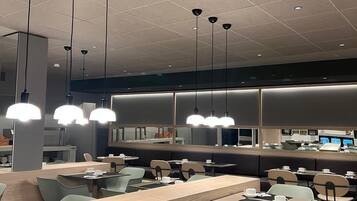 Un restaurante moderno con una barra larga, varias zonas de estar e iluminación colgante.