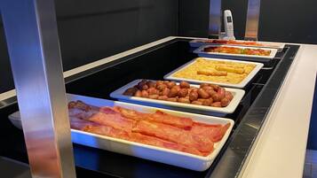 Un buffet proposant une variété de plats, notamment des œufs, du bacon et des viennoiseries.